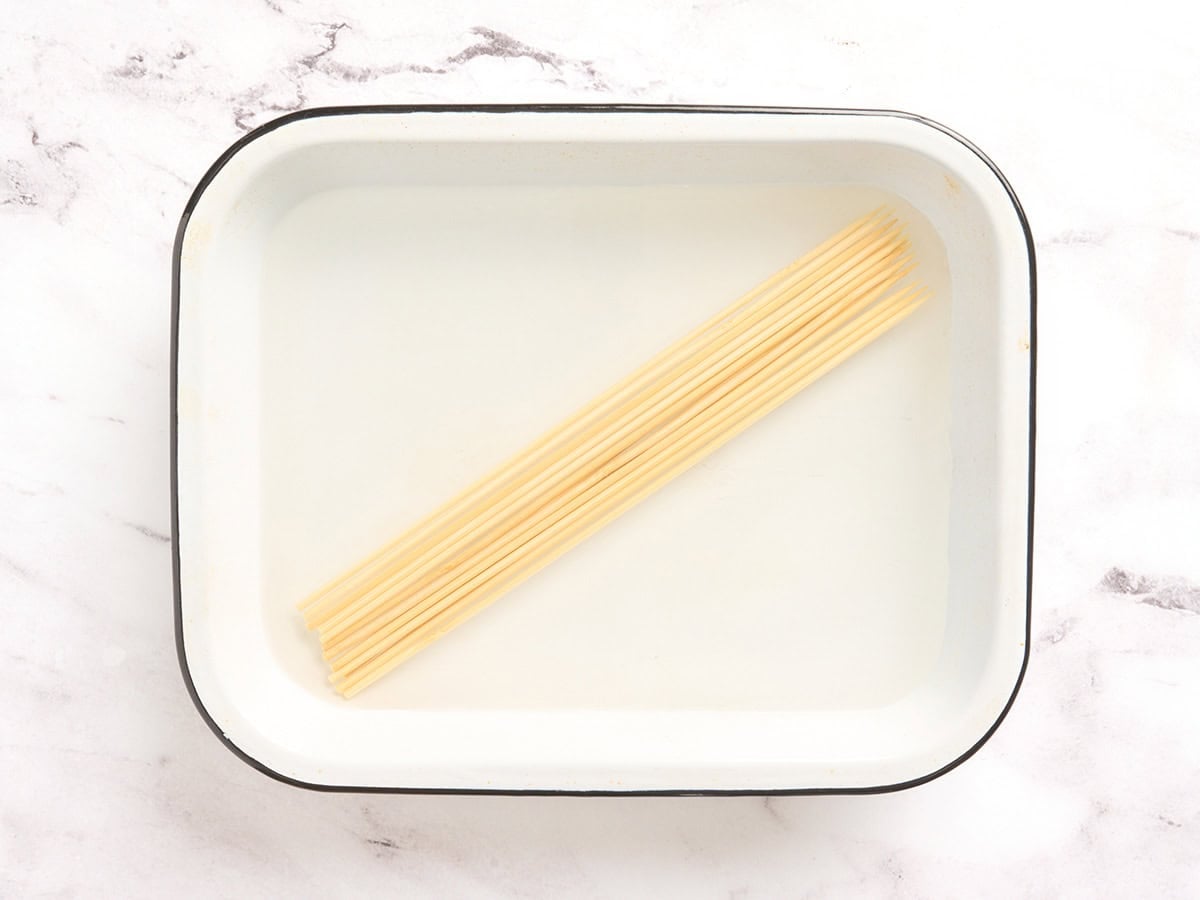 Wooden skewers in a shallow dish with water.