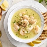 Shrimp and white bean stew in a bowl garnished with fresh herbs