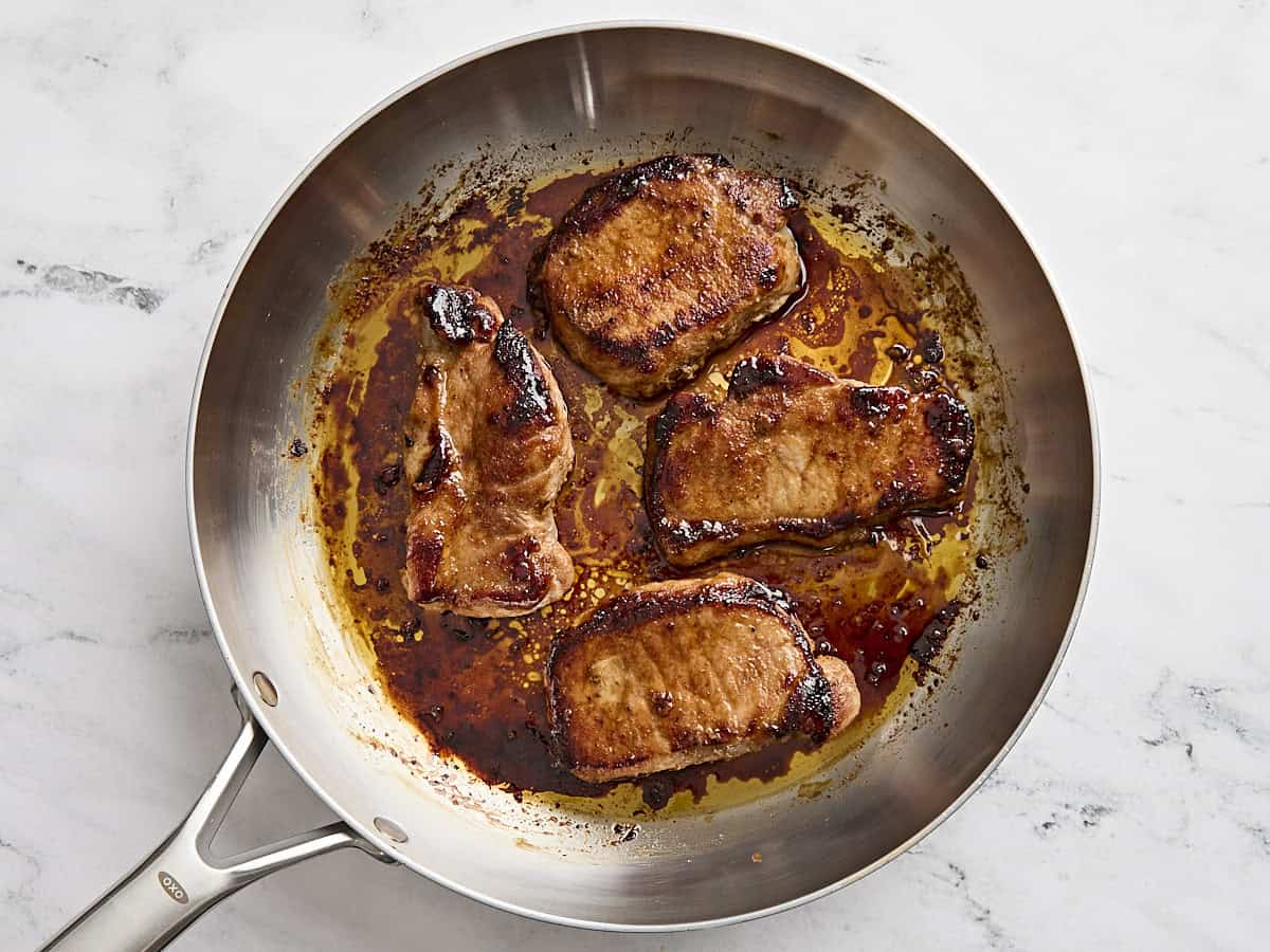 Finished glazed pork chops in a skillet.