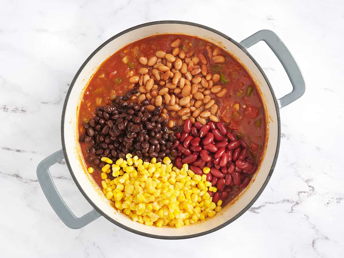 ingredients for vegetarian chili as beans and corn are being added to the pot