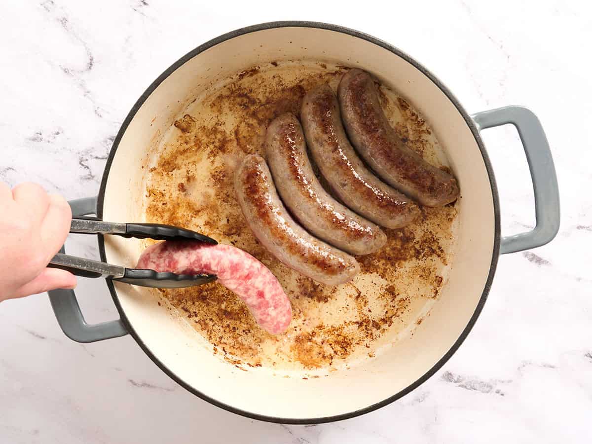 Brats being browned in a in a dutch oven.