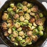 Overhead view of sauteed brussels sprouts in a cast iron skillet.