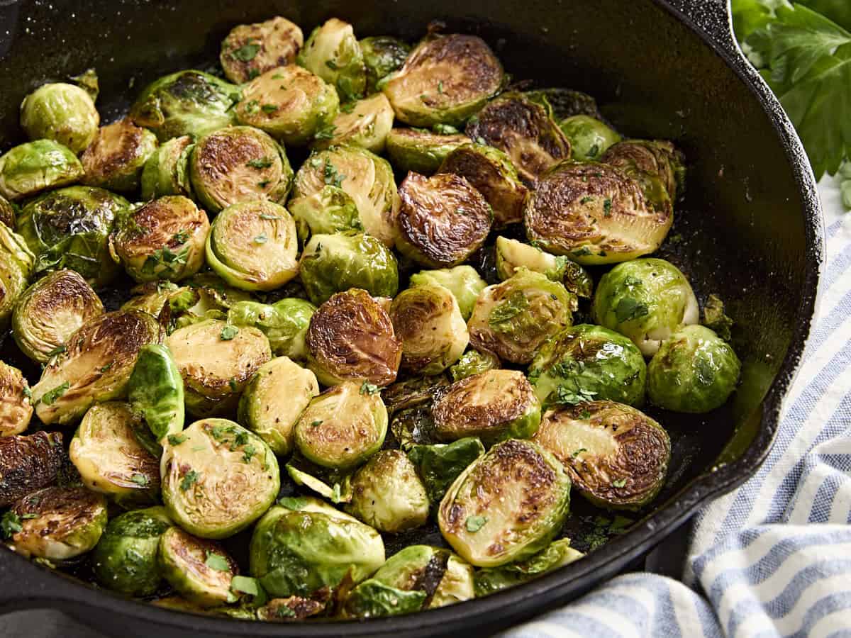 Side view of sauteed brussels sprouts in a cast iron skillet.