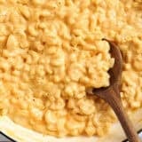 Overhead view of a pot of mac and cheese with a wooden spoon.