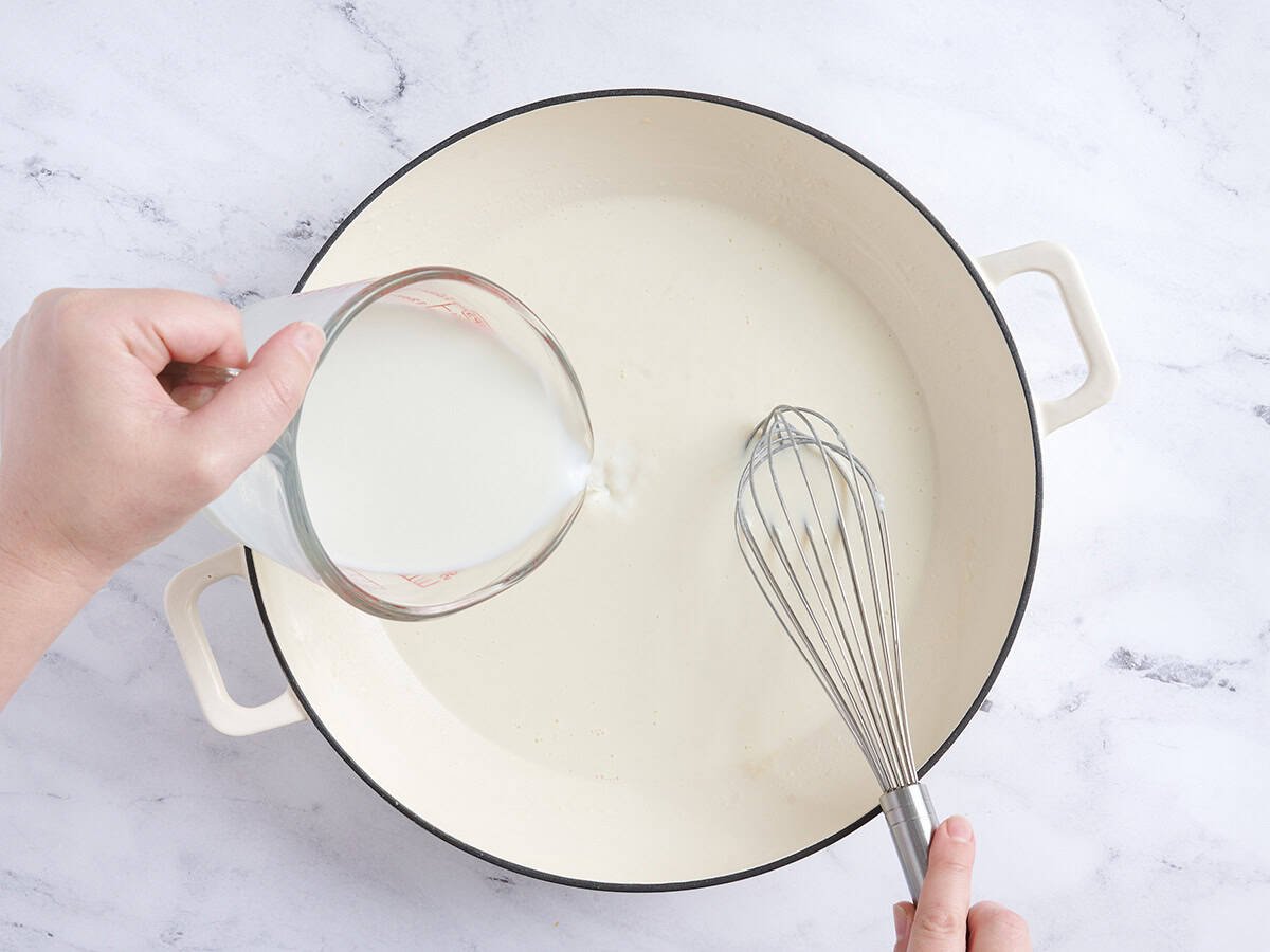 Milk being poured and whisked into a skillet.