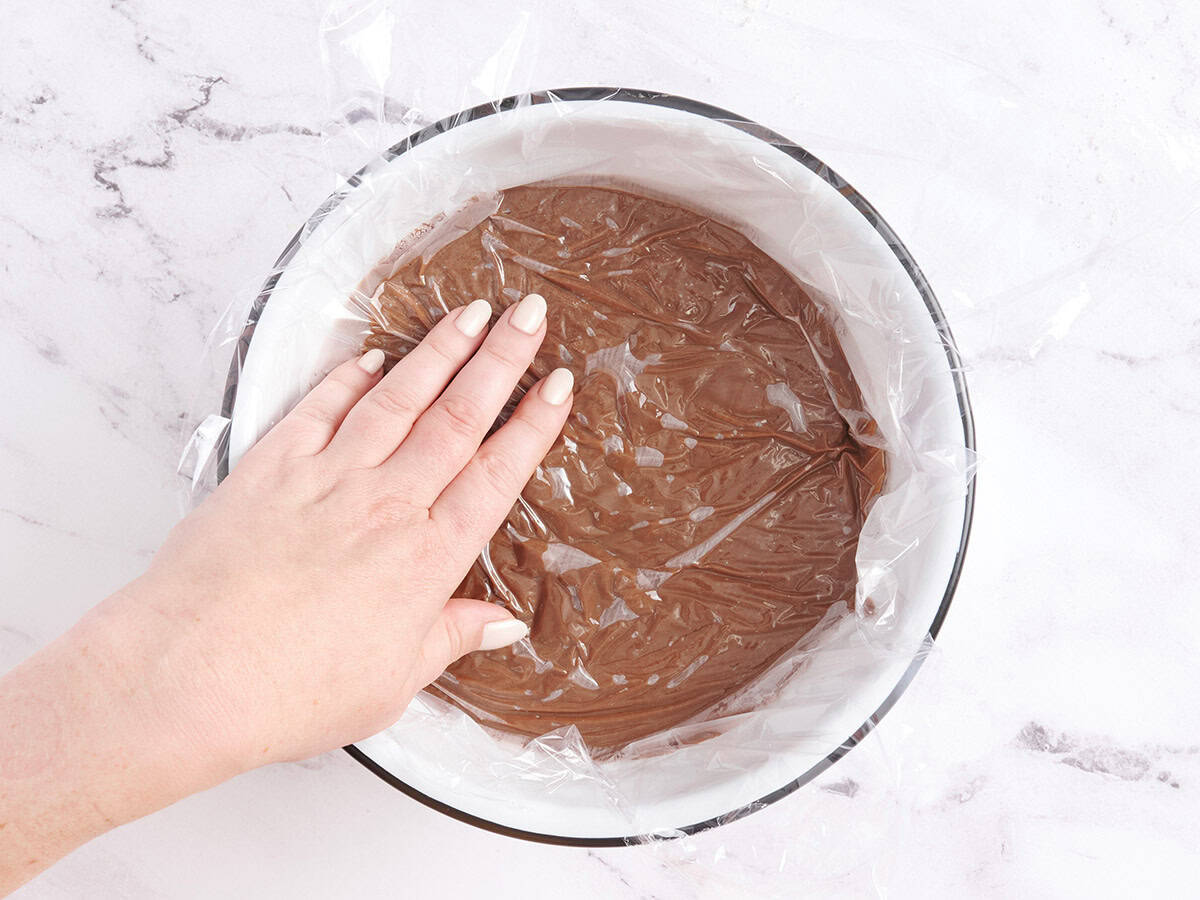 A bowl of chocolate pudding covered with plastic wrap.