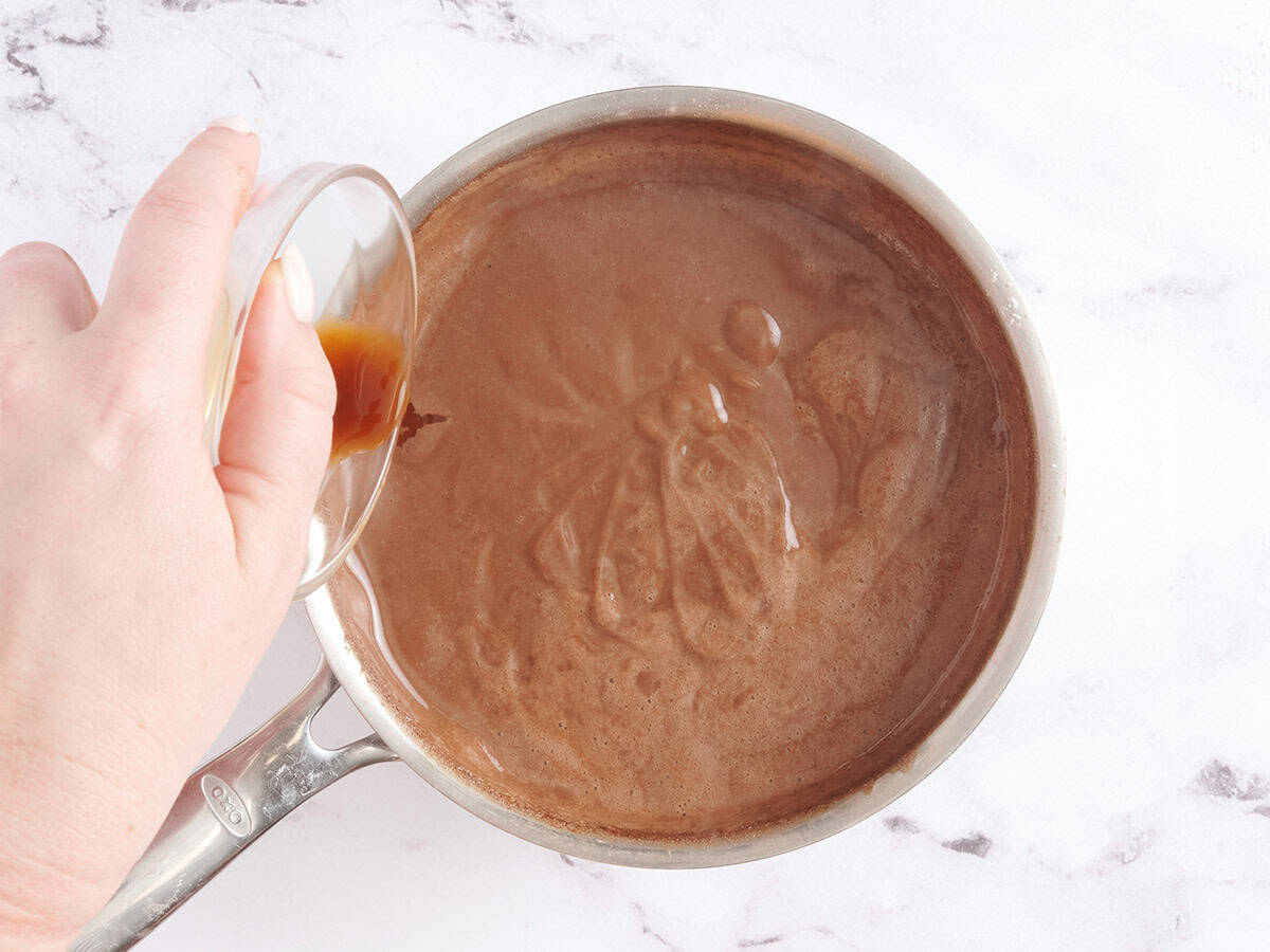 Vanilla extra being added to a saucepan of homemade chocolate pudding.