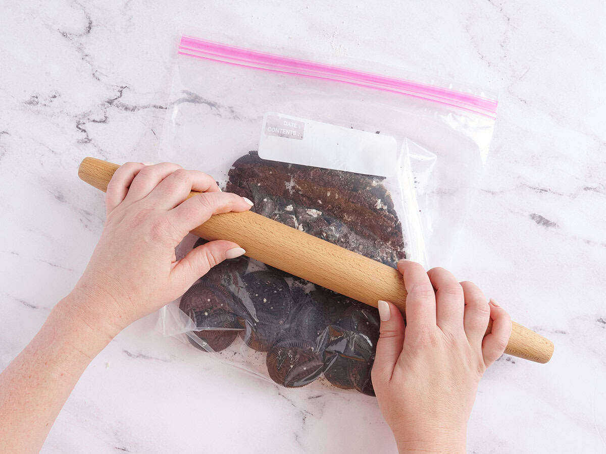 Chocolate sandwich cookies being crushed in a ziplock bag.