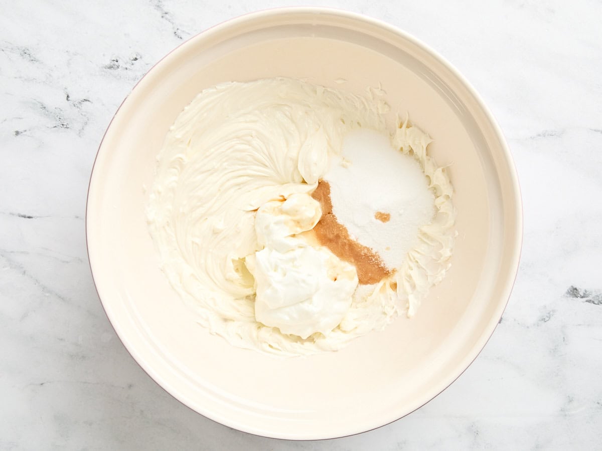 Cream cheese, greek yogurt, sugar, and vanilla extract in a bowl.