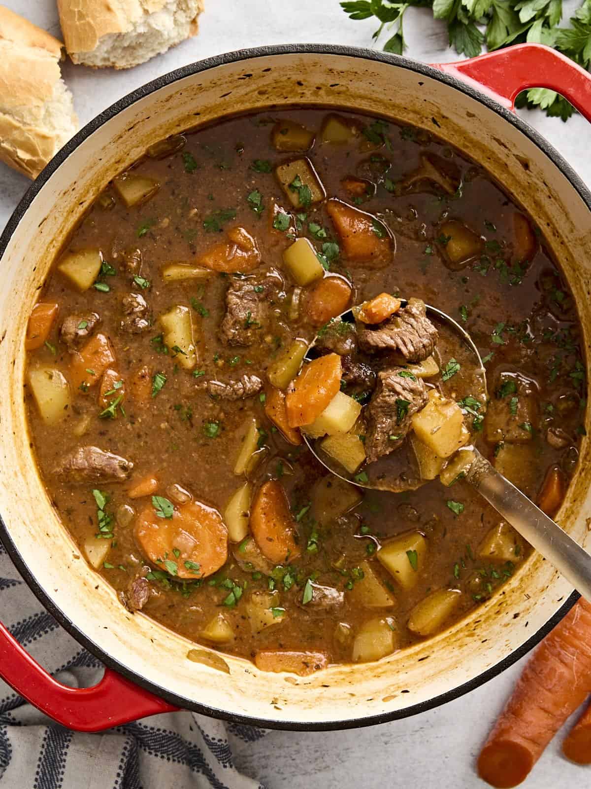 Overhead view of beef stew in a dutch oven with a ladle.