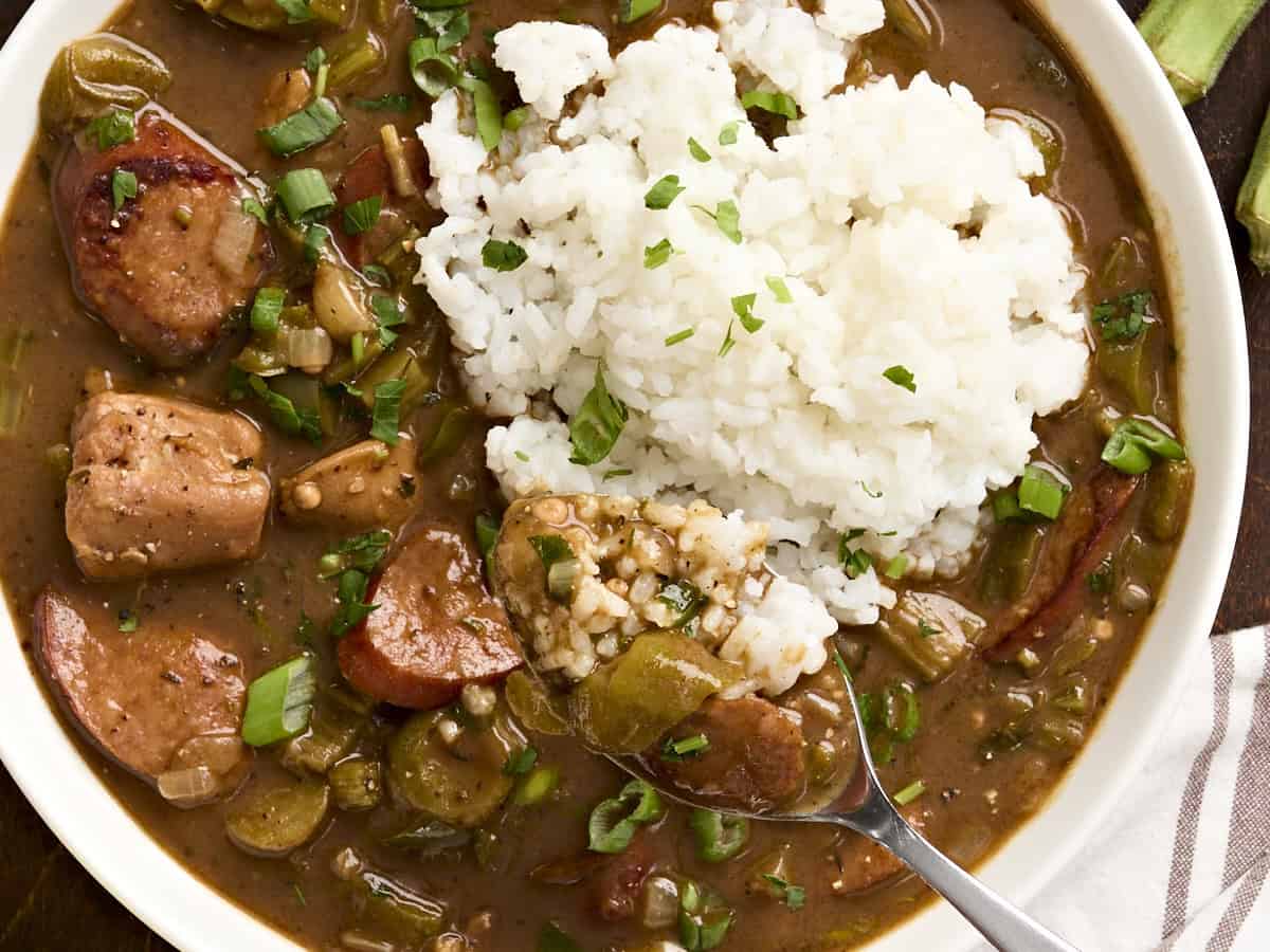 Overhead view of a bowl of gumbo and rice, with a spoon taking some.