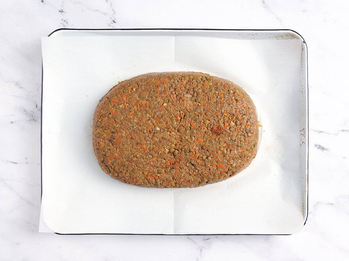 A shaped lentil loaf on a parchment lined baking sheet.