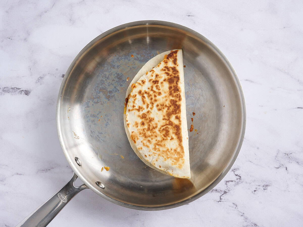A cheesy kidney bean quesadilla cooking in a skillet.