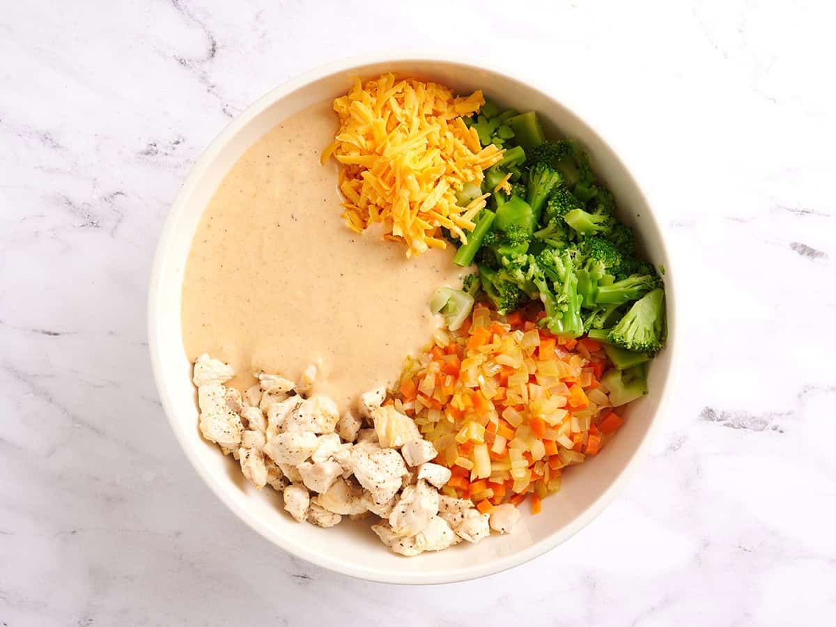 Chicken and rice casserole filling ingredients in a bowl with the sauce added