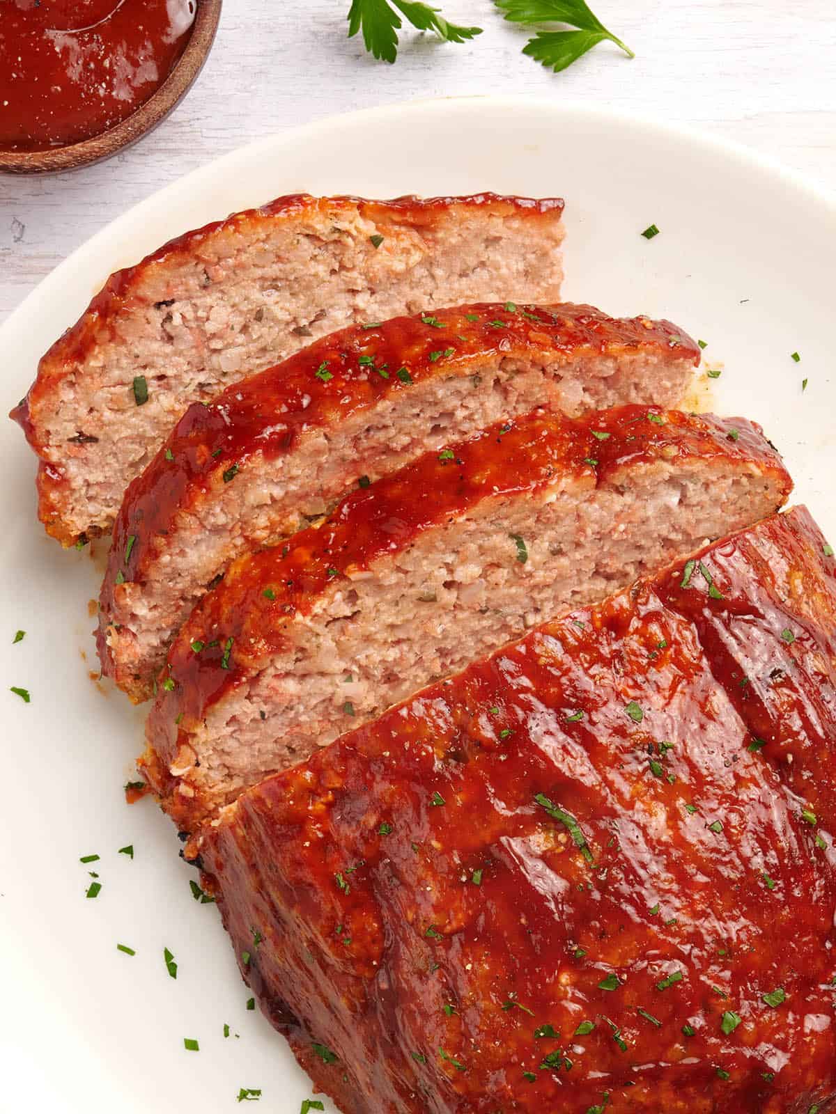 Slicked chicken meatloaf on a white platter. 