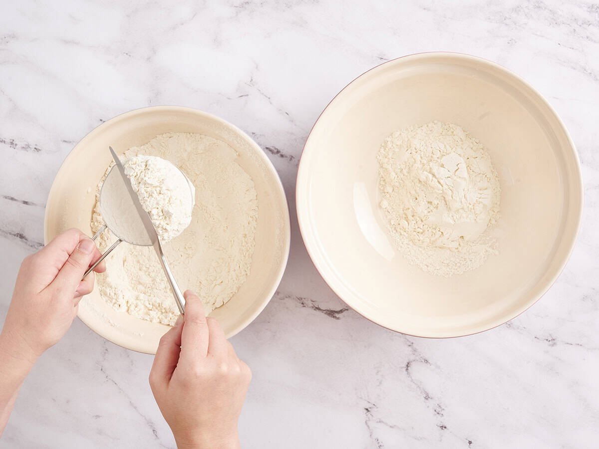 A knife levelling flour in a measuring cup.