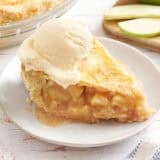 Side view of a slice of apple pie topped with a scoop of vanilla ice cream.