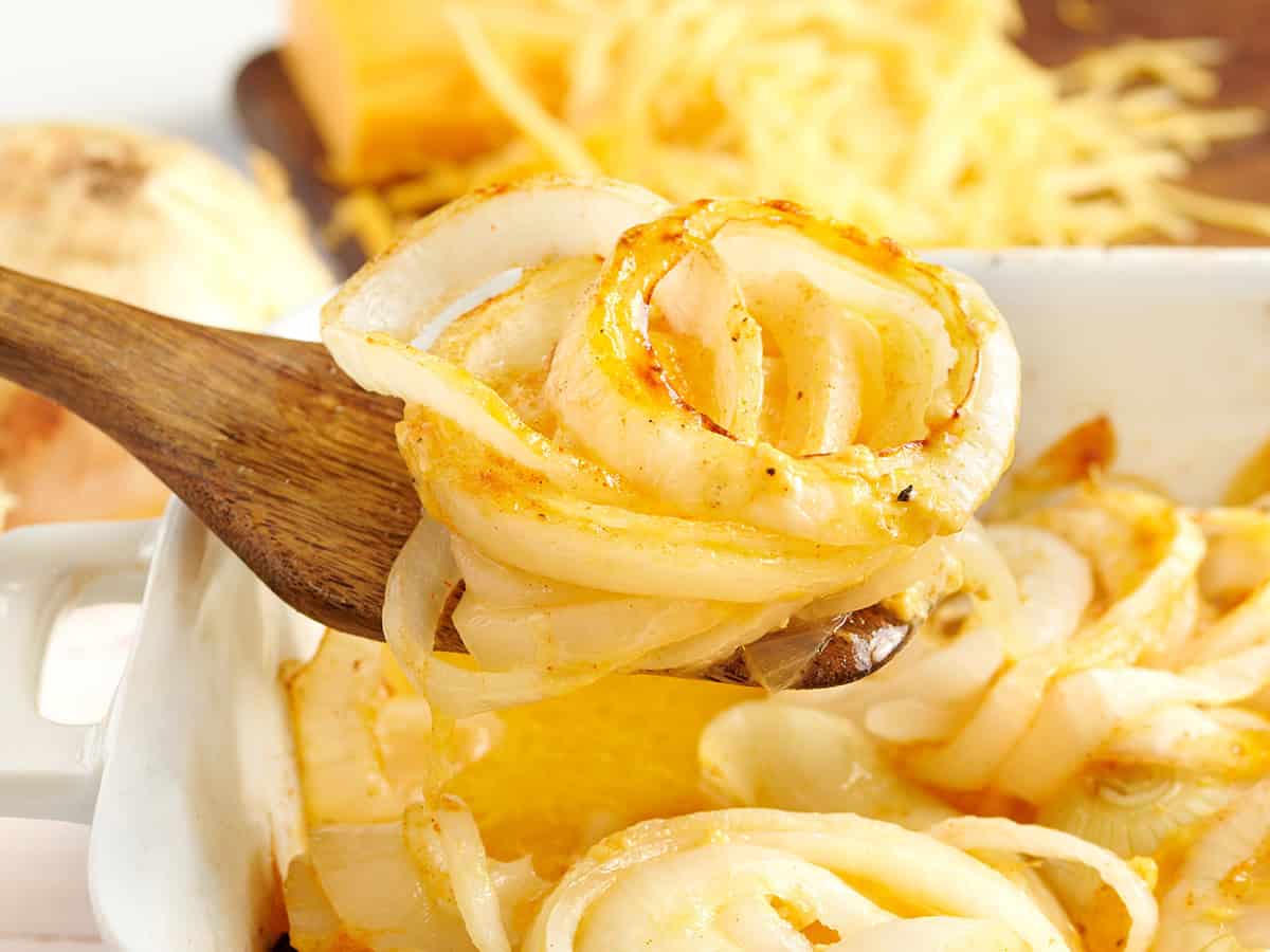 Side view of a baking dish of Tennessee onions with a spatula taking some.