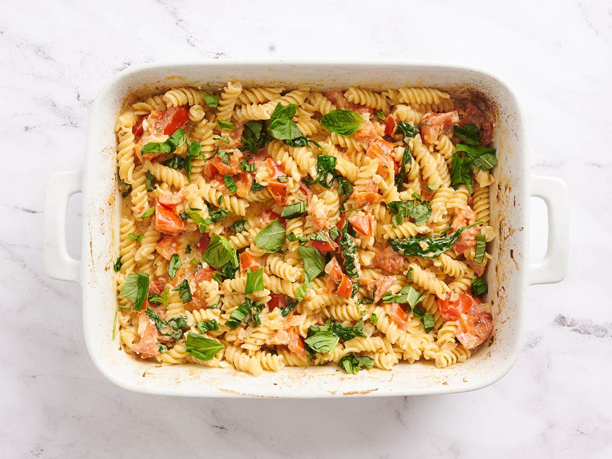 Finished baked feta pasta in a baking dish topped with basil.