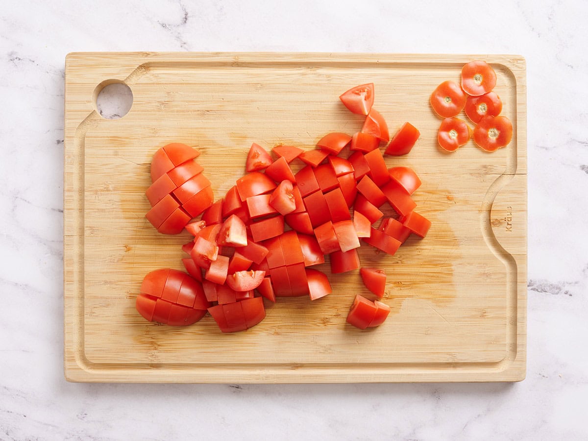Diced roma tomatoes on a wooden cutting board.
