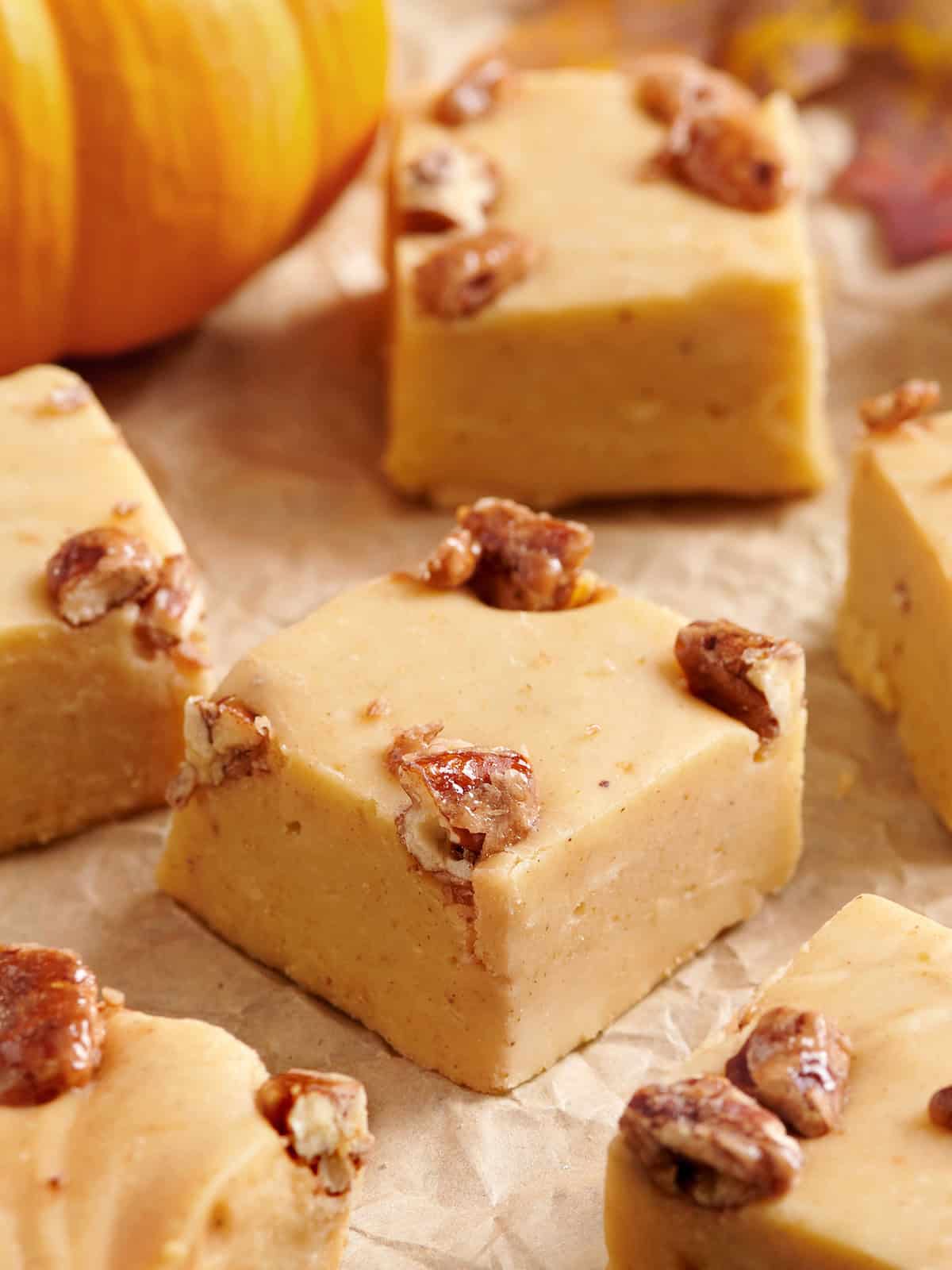 Side close up view of pumpkin spice fudge squares on parchment paper.