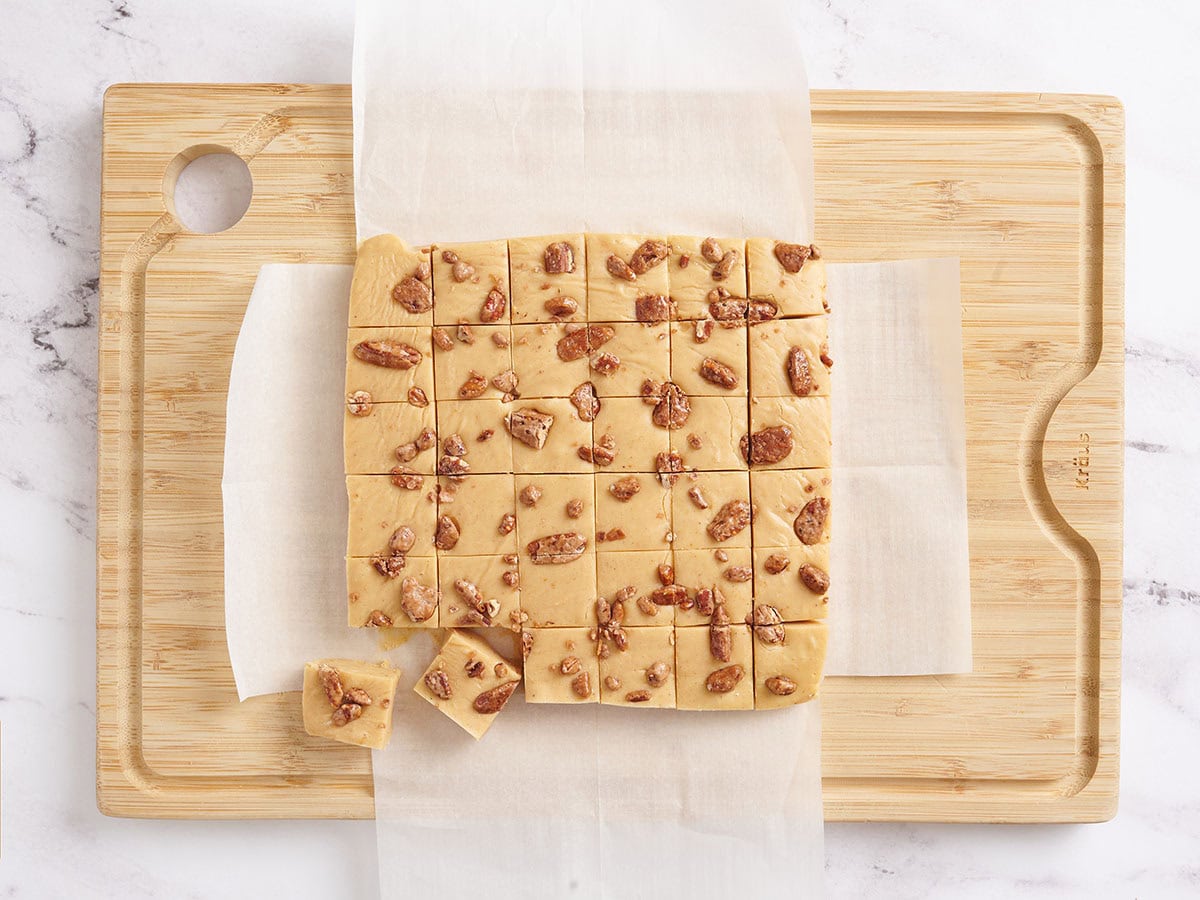 Homemade pumpkin spiced fudge cut into squares on a wooden cutting board.