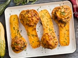 Overhead view of stuffed butternut squash on a baking tray.