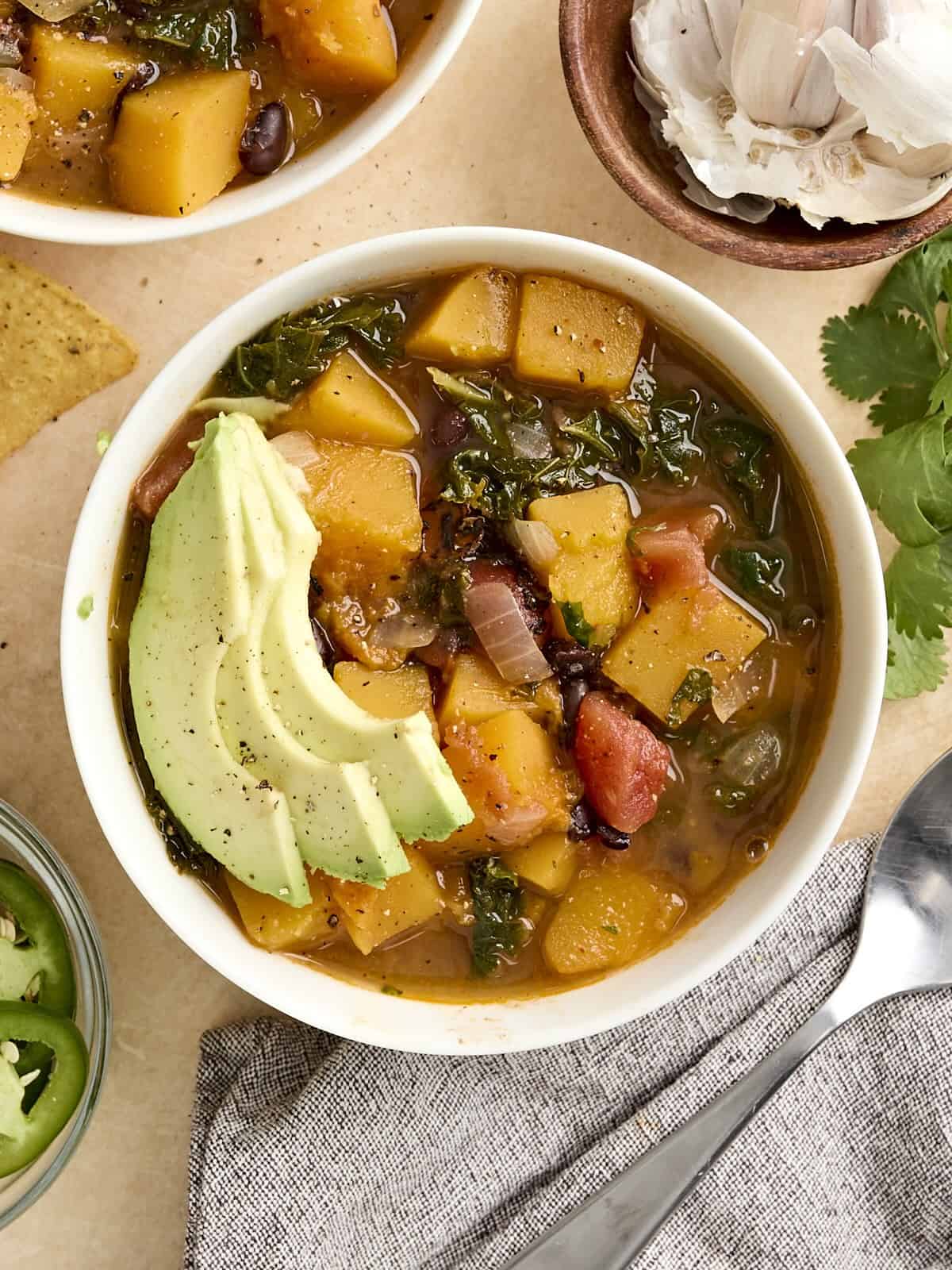 Overhead view of a bowl of butternut squash with black beans soup, topped with avocado.