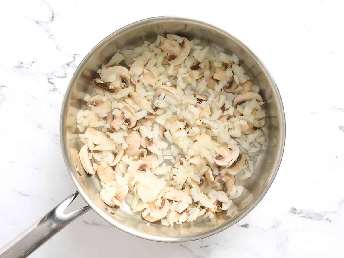 Mushrooms and onions in a skillet.