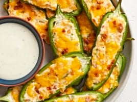 Super close up view of jalape&ntilde;o poppers on a plate with a bowl of ranch.