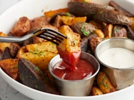 fork dipping an air fryer potato into ketchup.