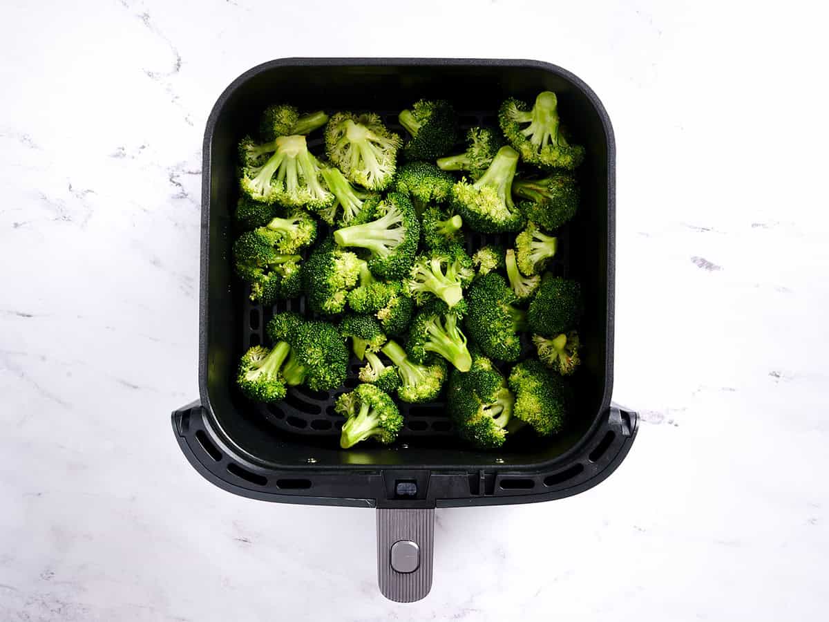 Broccoli florets in a air fryer basket.