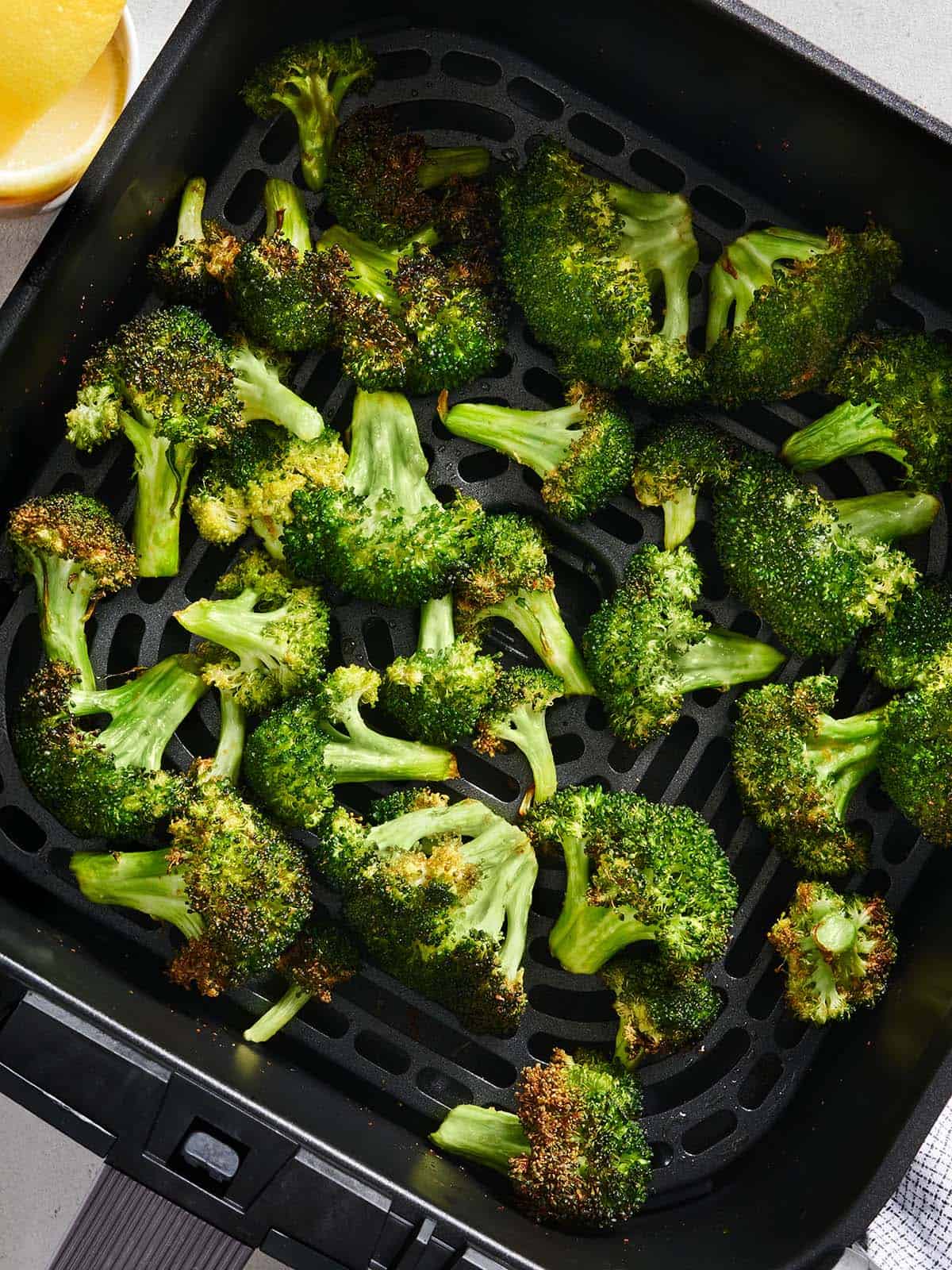 Overhead view of air fryer broccoli in a air fryer basket.