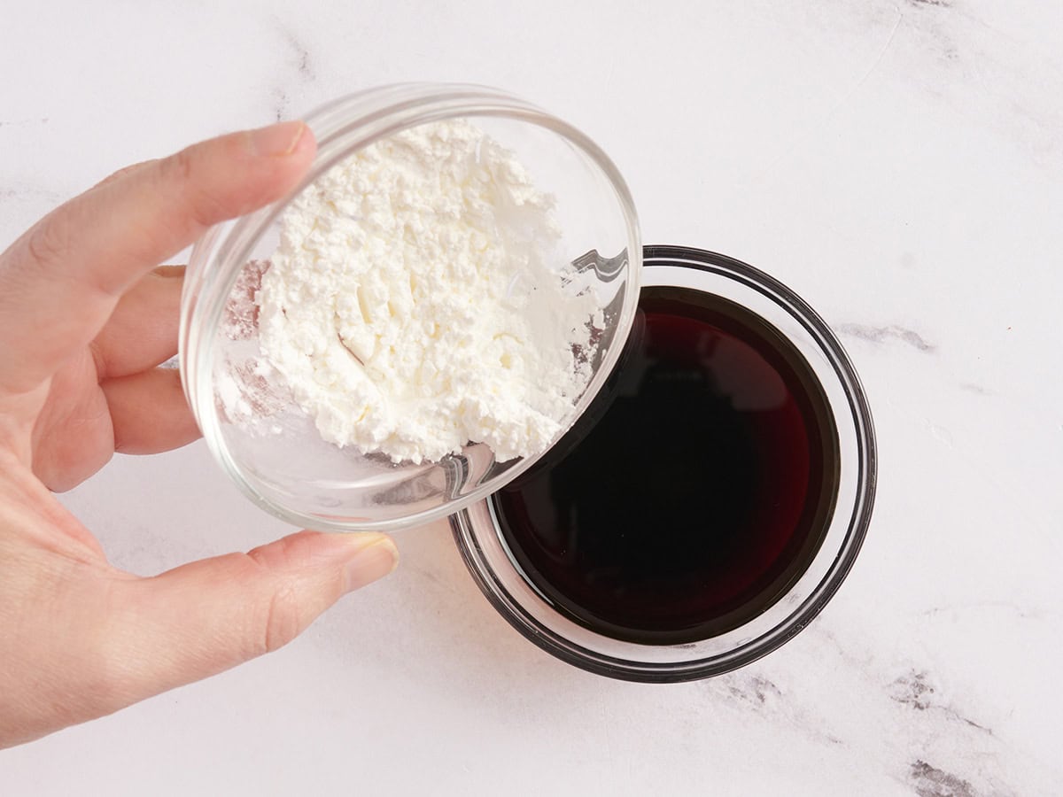 Corn starch being poured into soy sauce.