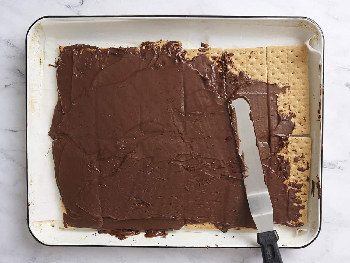 Covering the graham crackers with the melted chocolate. 