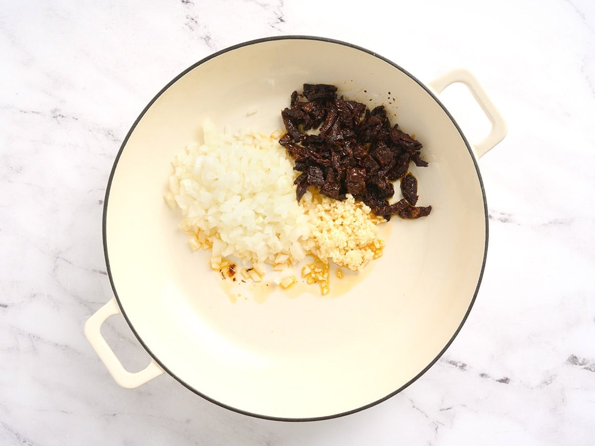 Minced garlic, diced onion and minced sun dried tomatoes in a pot.