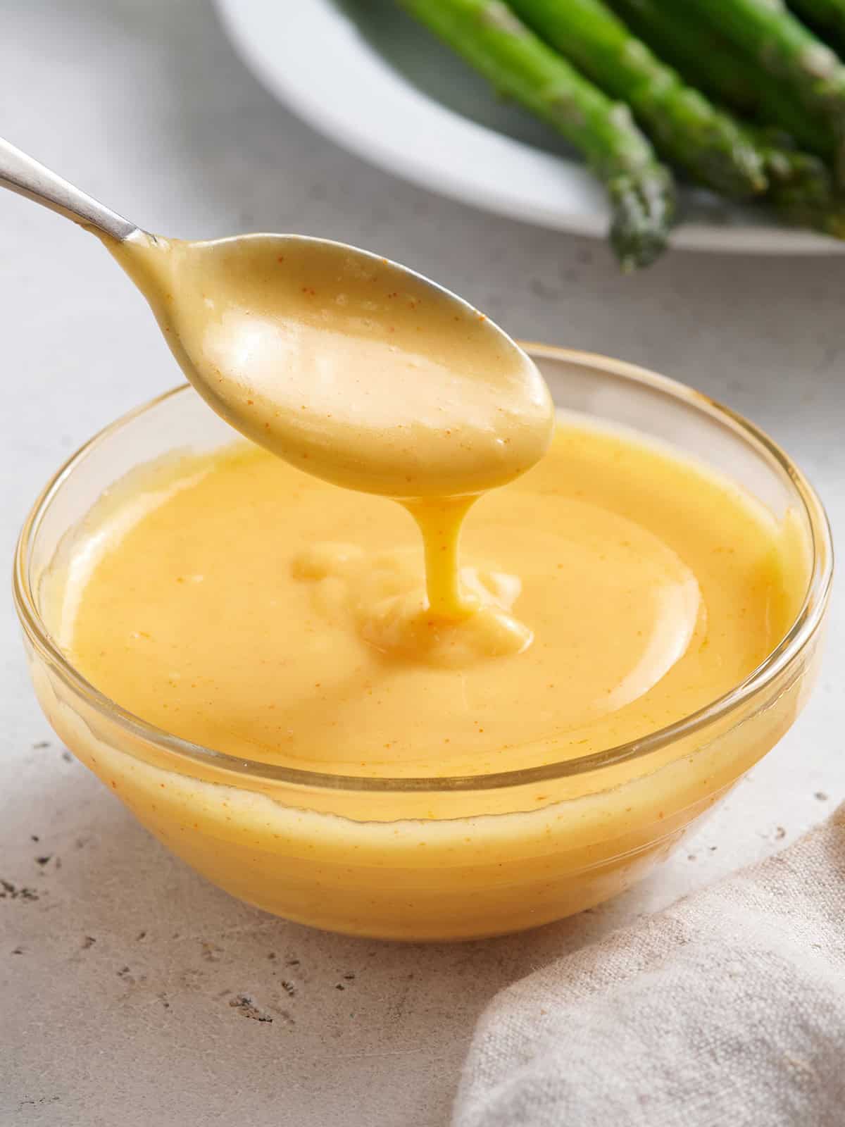 Homemade hollandaise sauce in a bowl with a spoon.