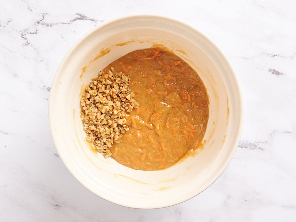 Walnuts added to carrot cake bar batter in a mixing bowl.