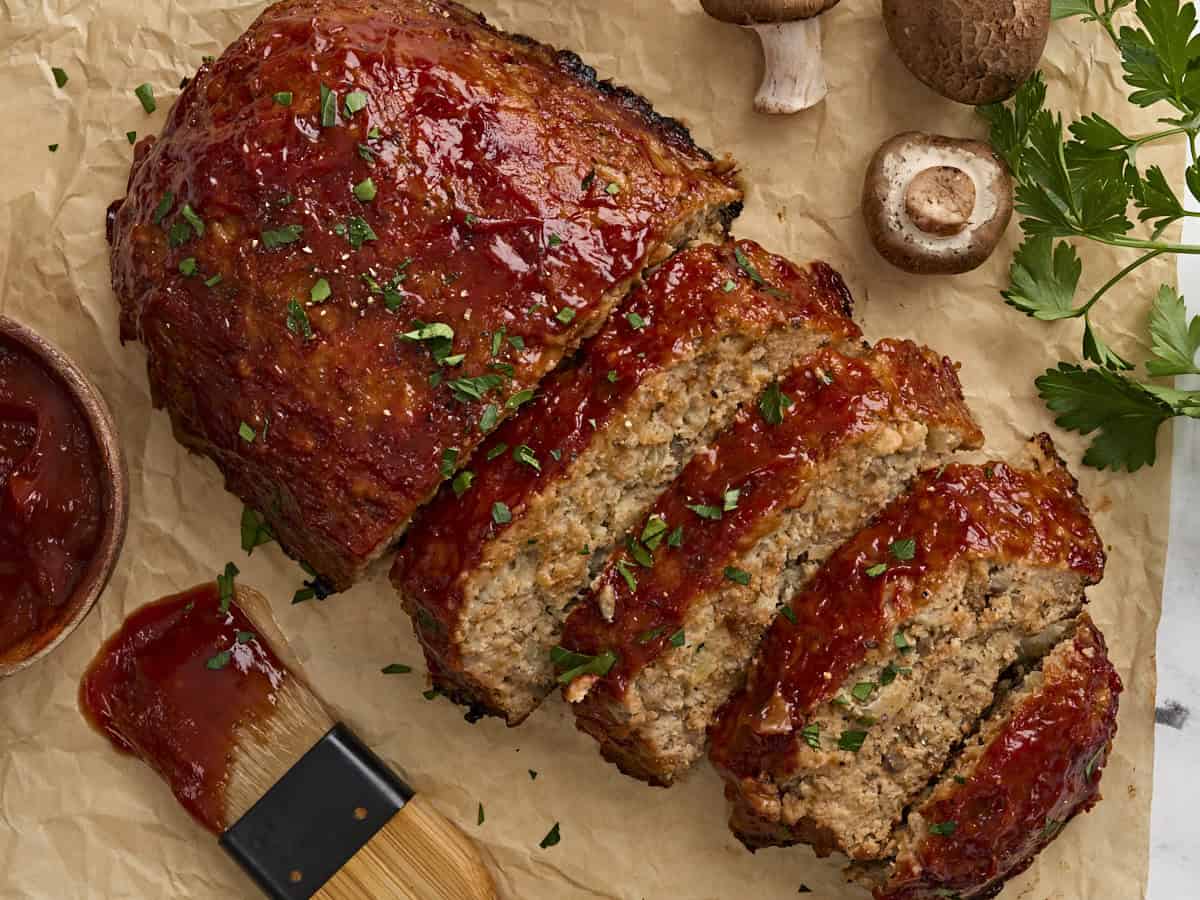 Overhead view of a homemade turkey mushroom meatloaf, with half of it cut into slices.