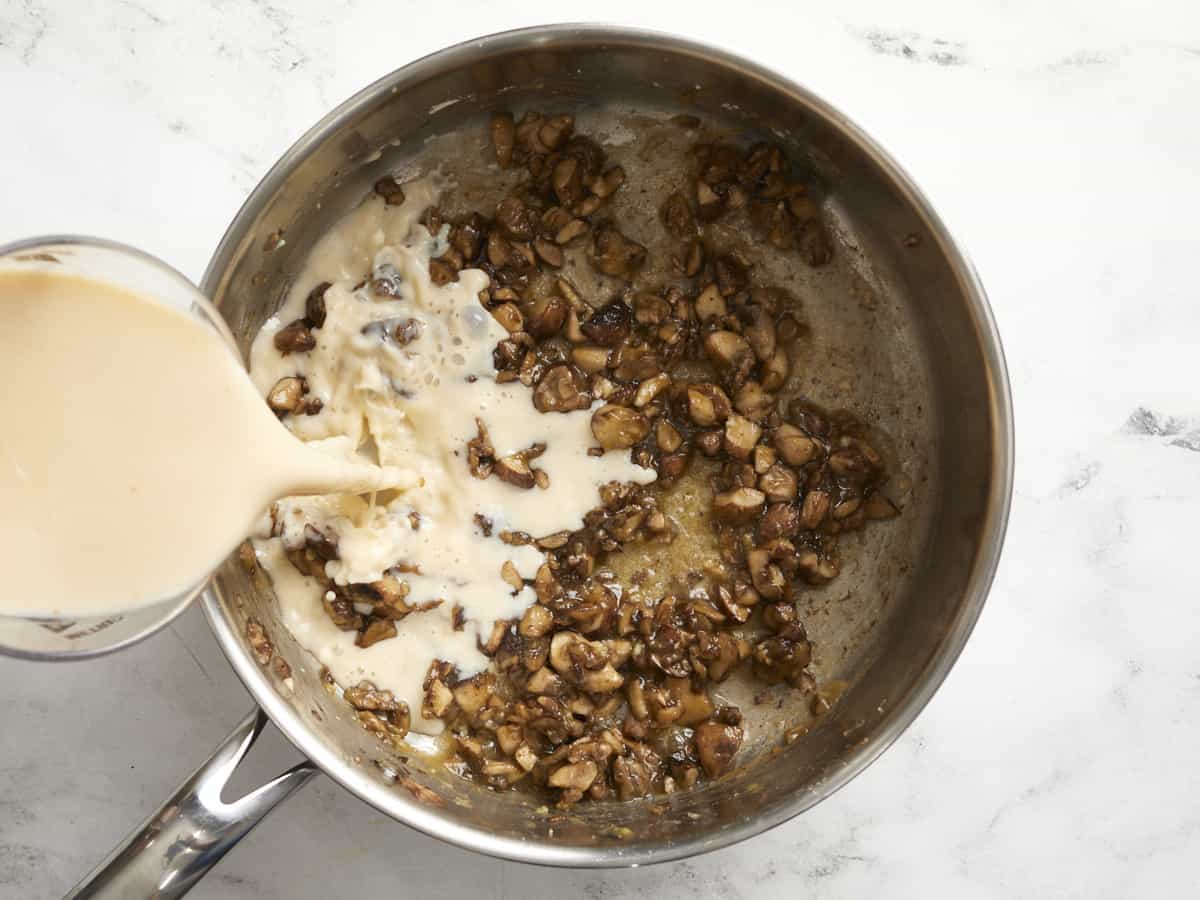 Milk and broth being poured into the skillet. 