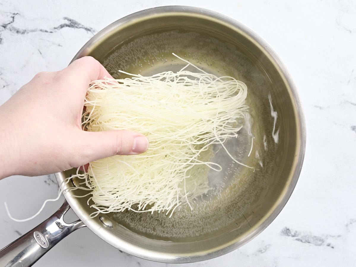 Noodles being added to a pot of water.