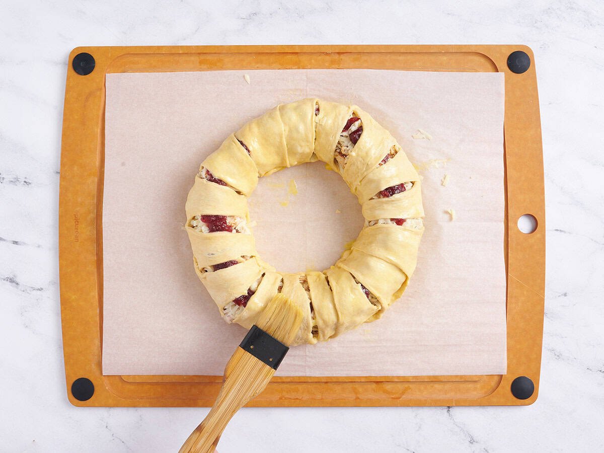 Brushing an egg wash over the wreath.