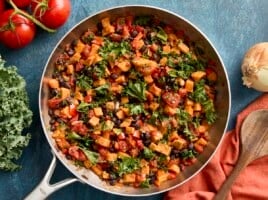 Overhead view of sweet potatoes and black bean skillet with napkin and wooden spoon on the side.