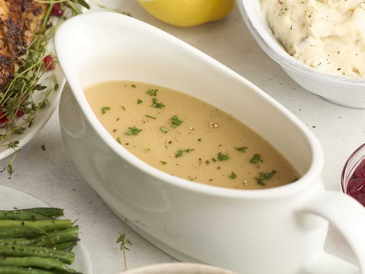 Side view of turkey gravy in a gravy boat topped with fresh parsley.