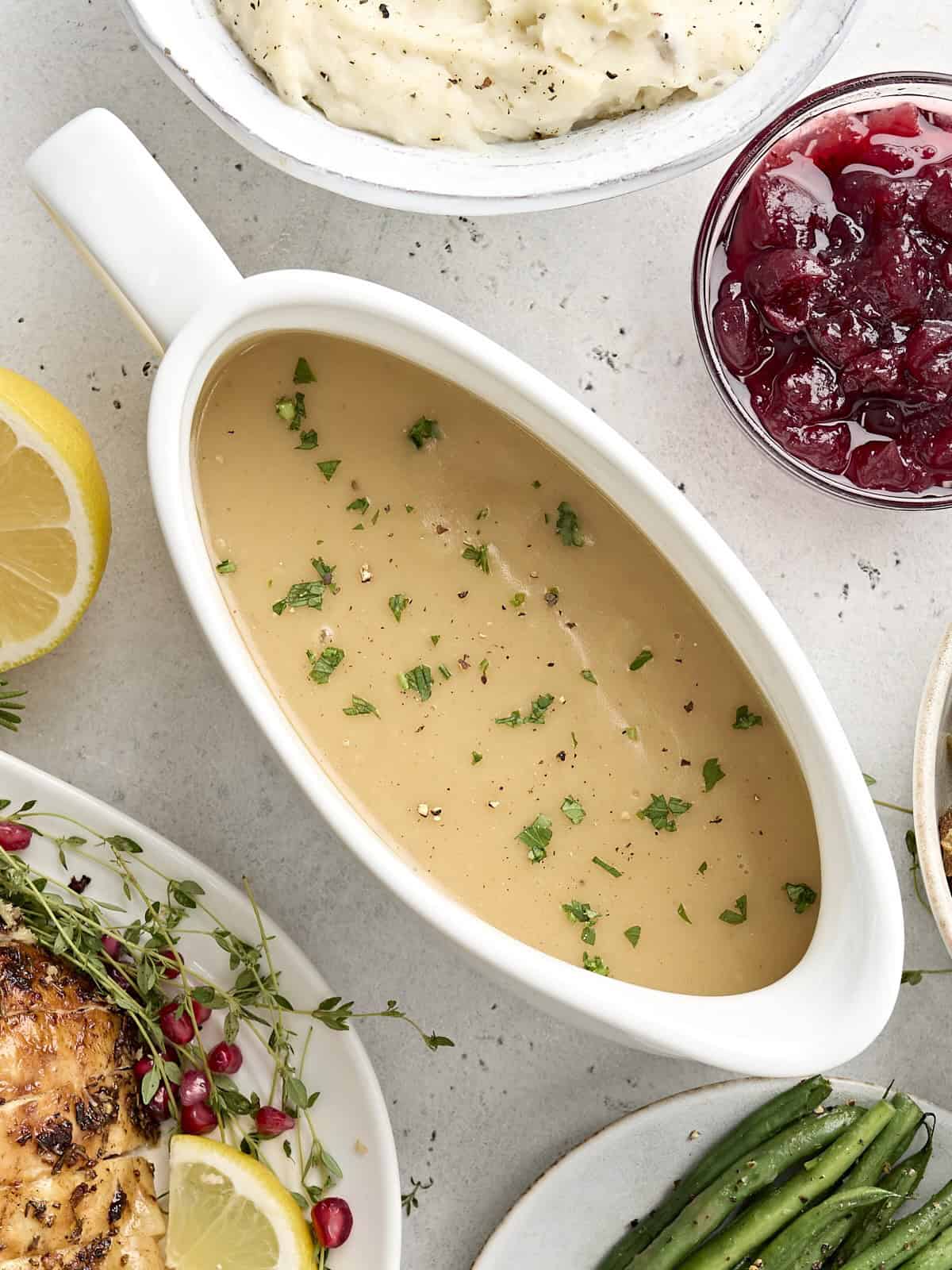 Overhead view of turkey gravy in a gravy boat sprinkled with fresh parsley.