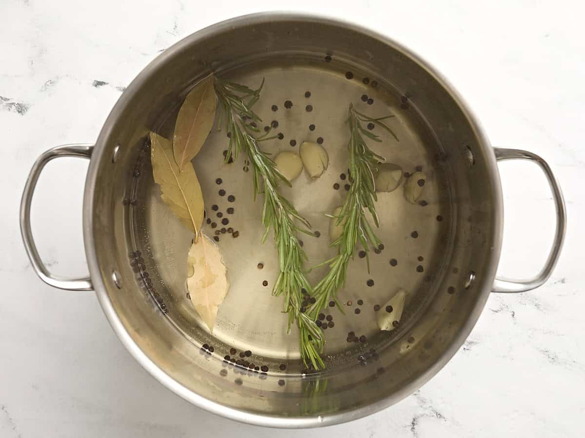 Herbs being simmered in a large pot of water.