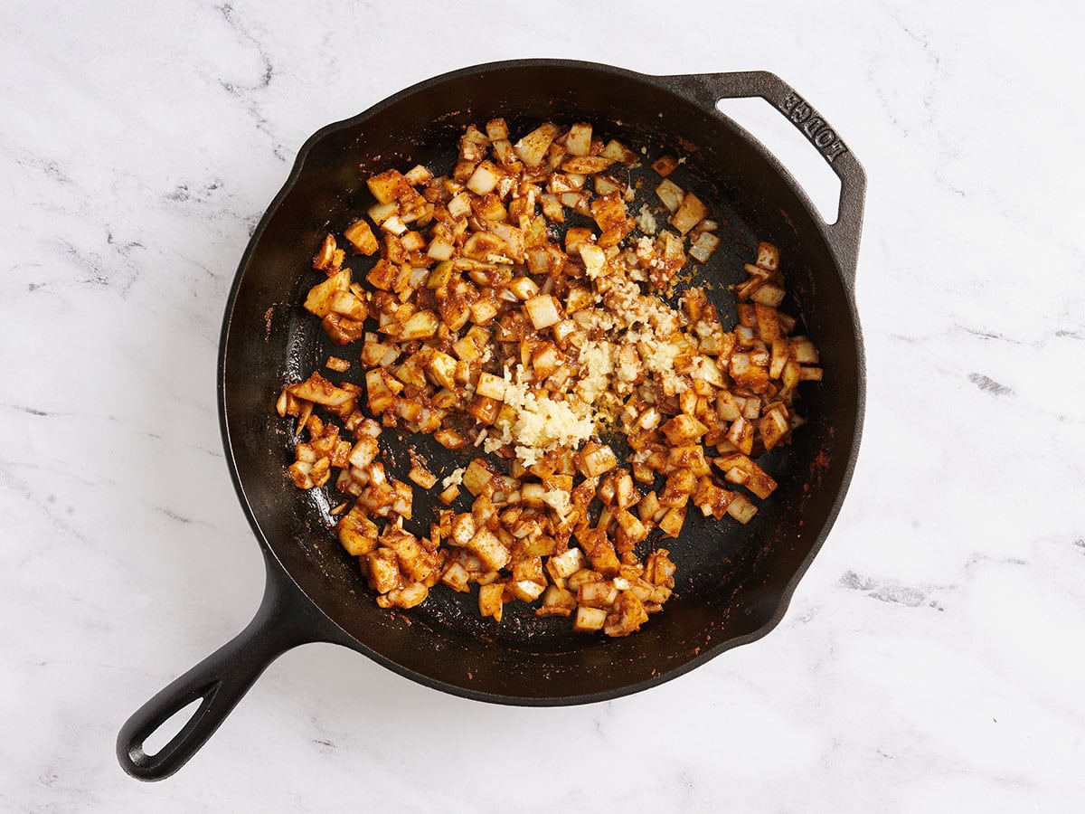 Sauteed onions, garlic, and ginger in a skillet with spices.