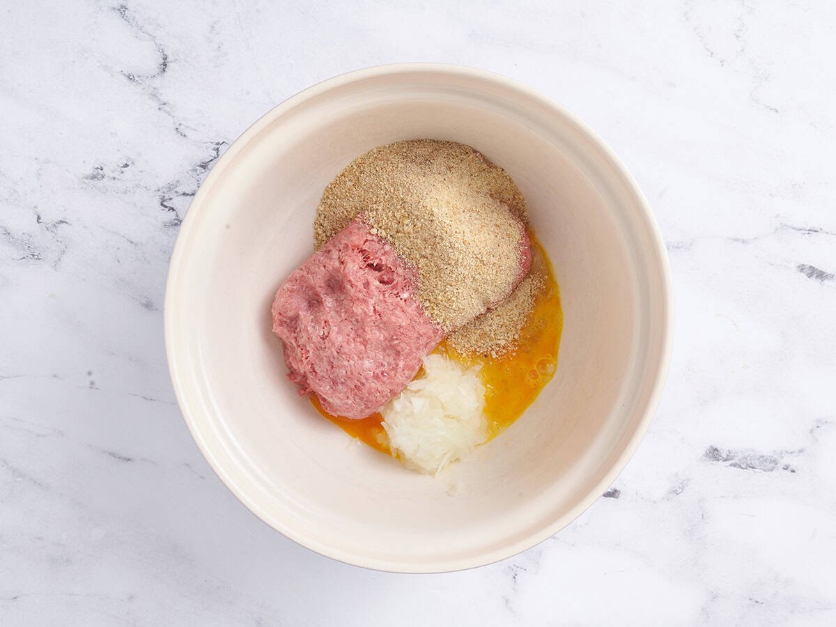 Breadcrumbs, seasonings and ground meat in a mixing bowl.