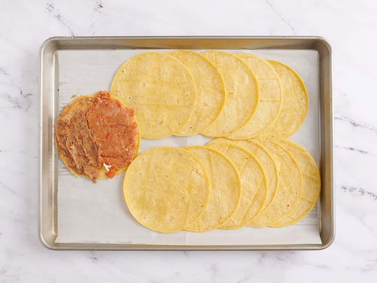 Refried beans added to the other half of a tortillas next to a turkey meat mixture.