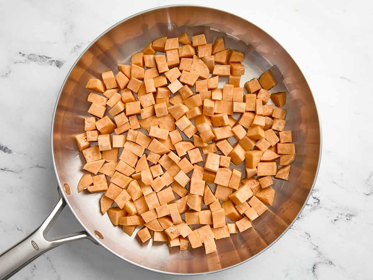 Chopped sweet potatoes added to a large skillet.